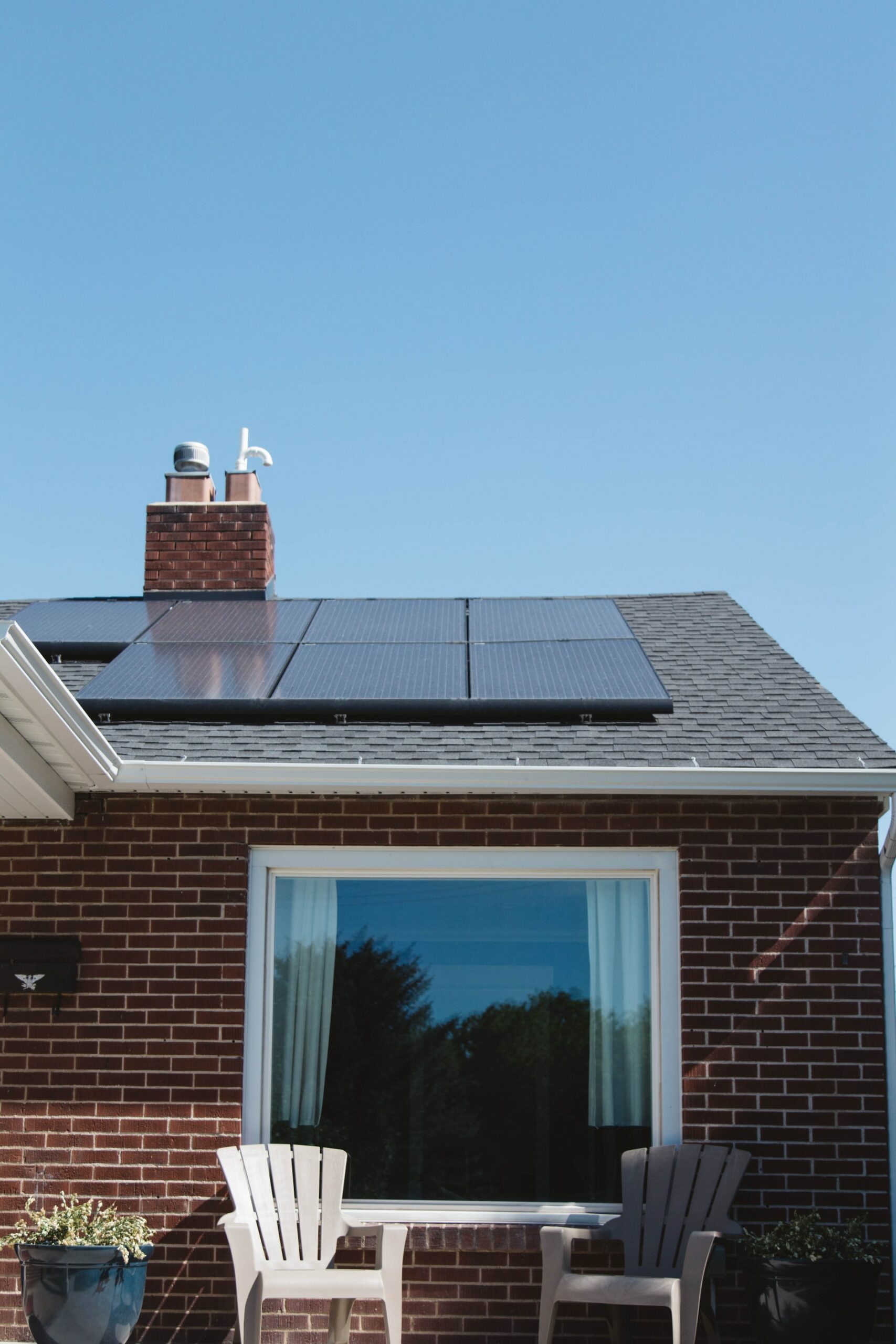 Solar PV panels on the roof of a house above a large window.