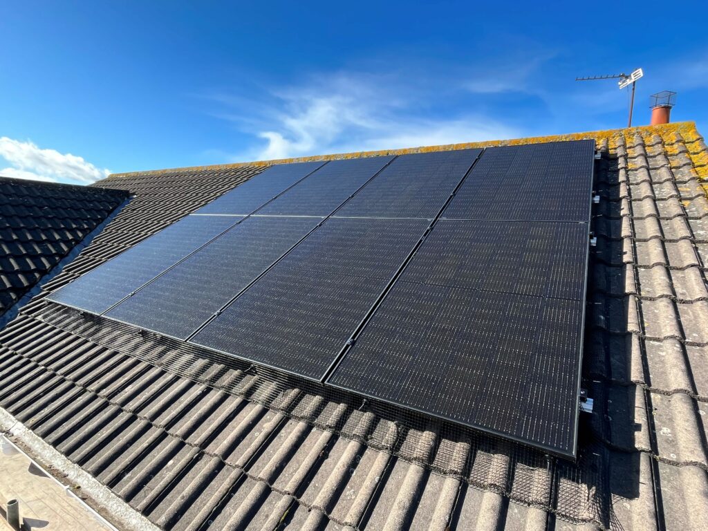 Solar PV panels installed on a roof with sky in the background.
