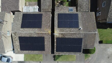 Direct overhead of four groups of solar PV panels installed on two roofs.
