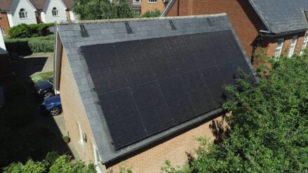 Solar PV panels installed on a steeply slanted roof in a residential area.