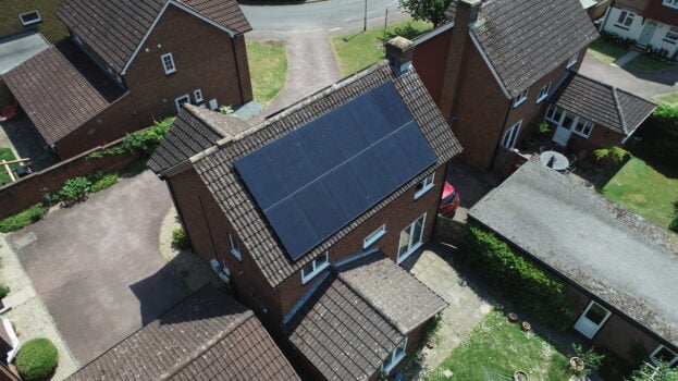 Overhead of a detached house with solar PV panels on the roof in a residential area.