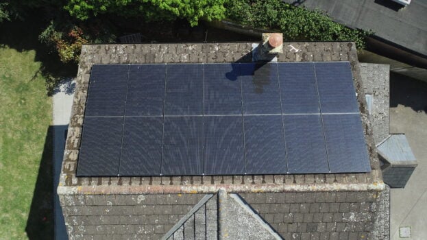 Direct overhead of solar PV panels installed on a roof next to a chimney.