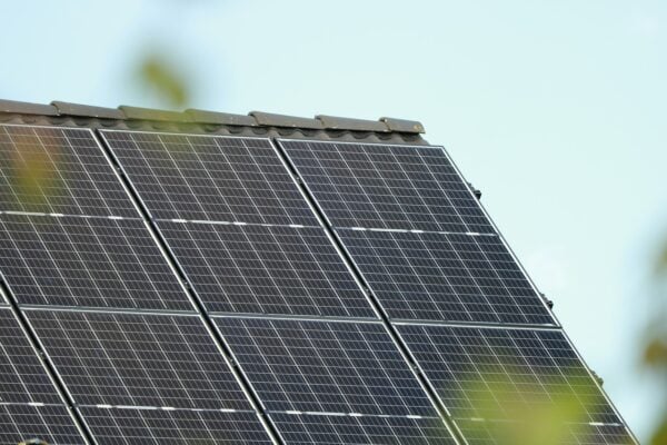 Solar panels on the roof with greenery in the foreground.